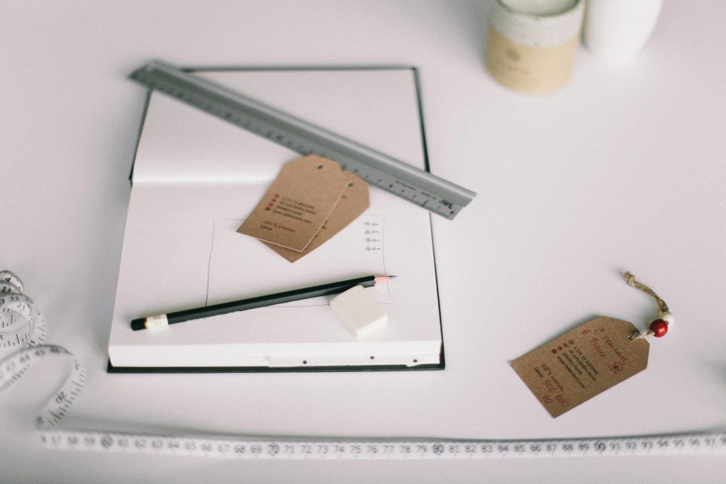 Minimalist workspace featuring a notebook, pencil, and paper tags. Perfect for design or planning concepts.
